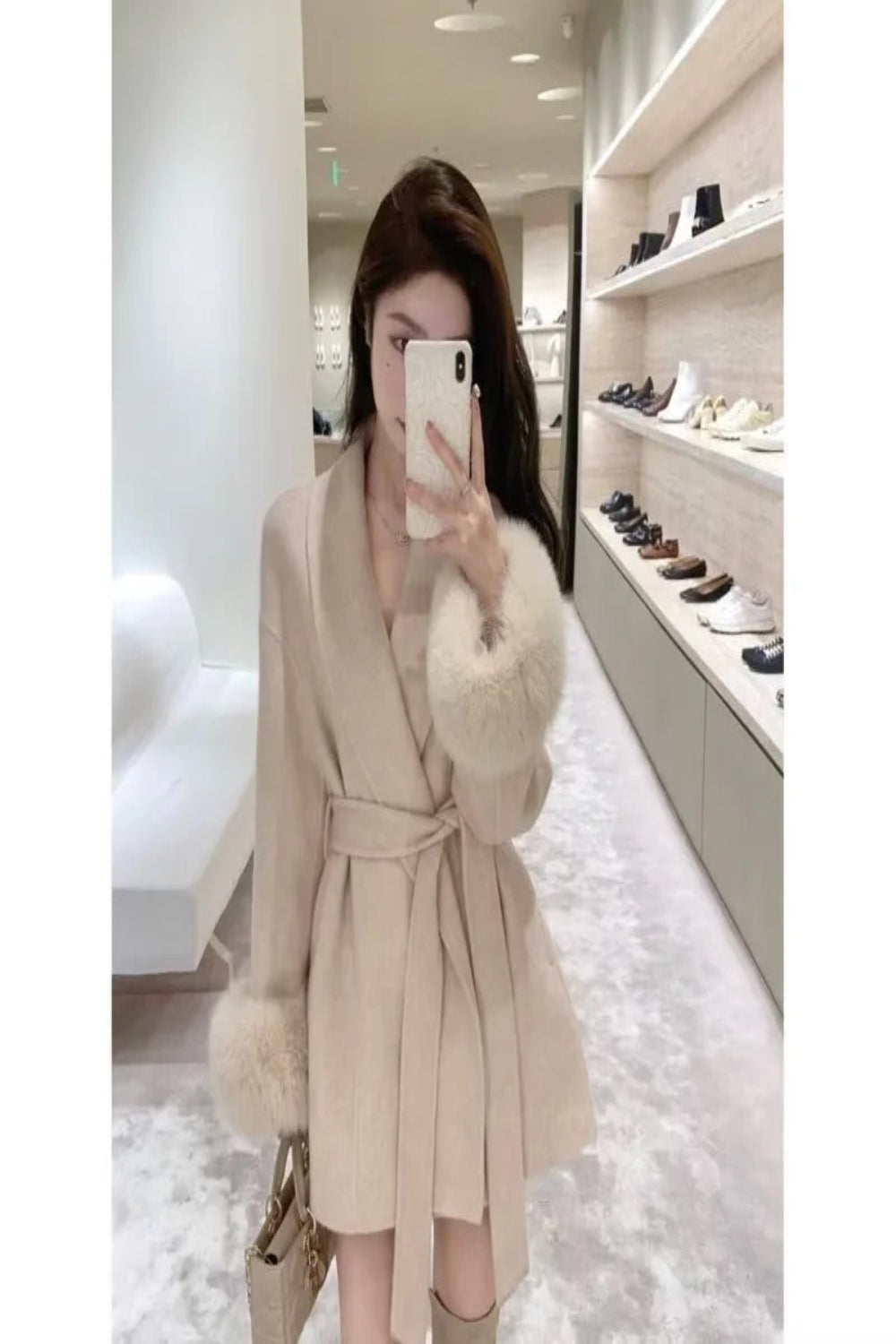 Person wearing a beige coat with fur trim in a store setting