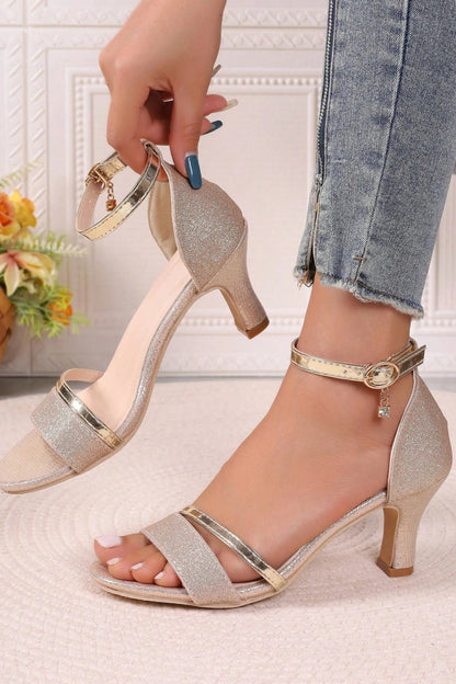 Silver glitter high-heeled sandals being worn on a light background
