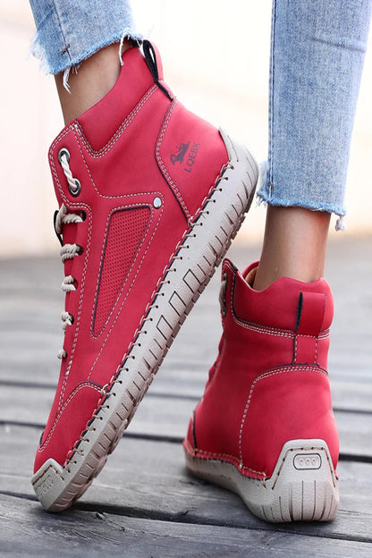Red high-top sneakers with beige soles on a wooden floor