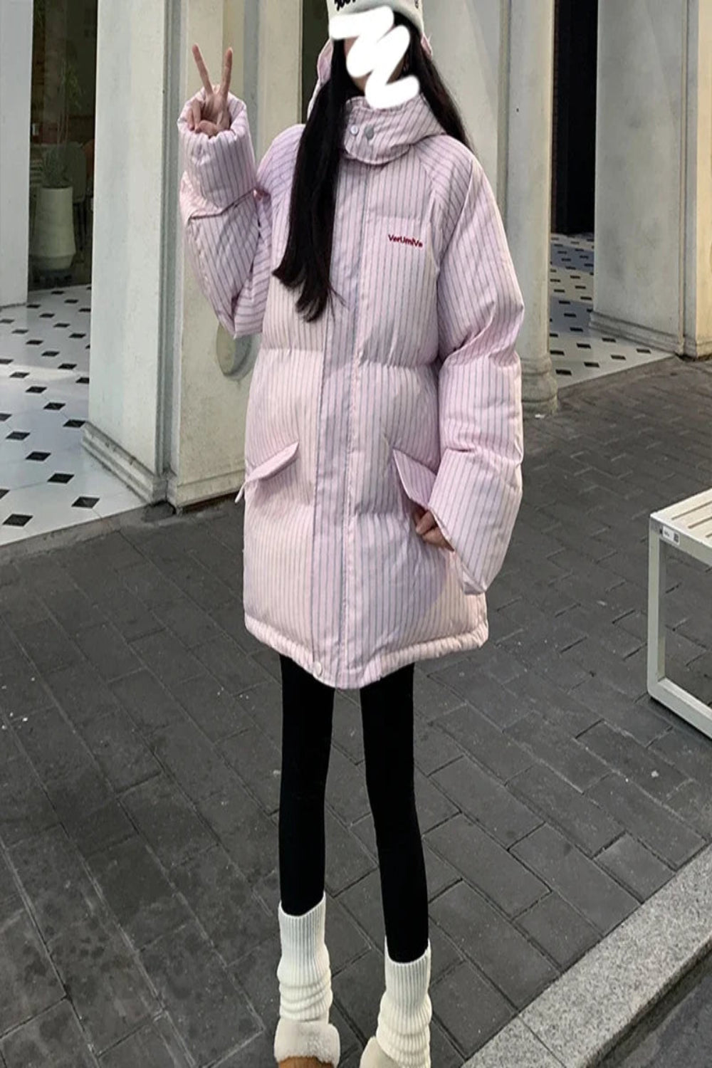 Person wearing a pink striped puffer jacket outdoors on a sidewalk.