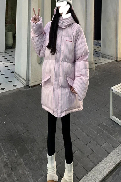 Person wearing a pink striped puffer jacket outdoors on a sidewalk.