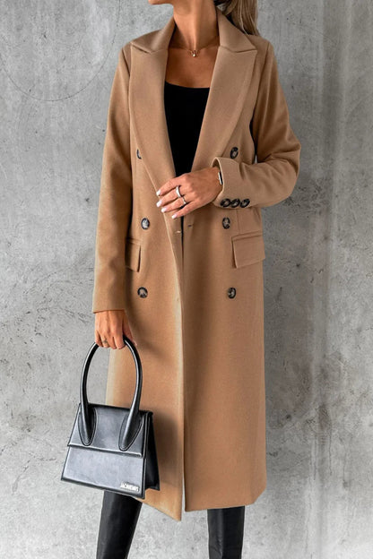 Person wearing a beige coat holding a black handbag against a gray background