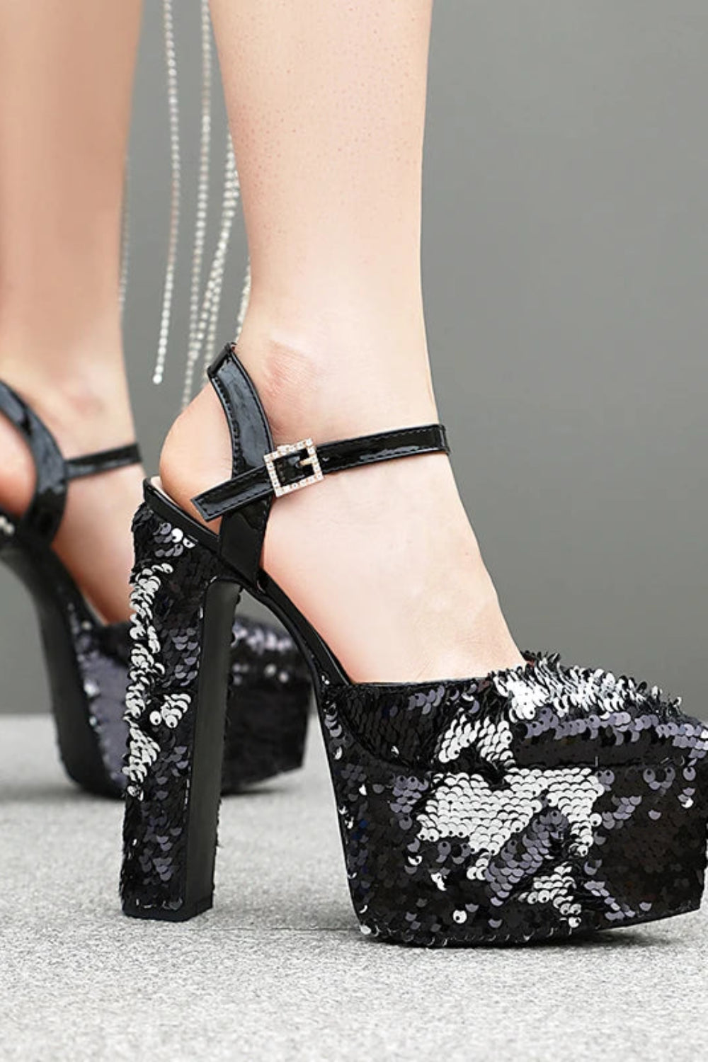 Black sequin high-heeled shoes with platform on a neutral background