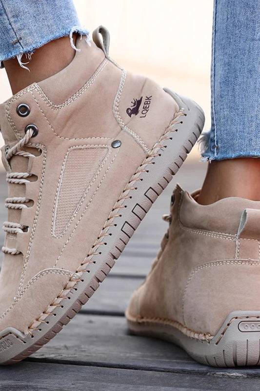 Beige boots worn with light blue jeans on a wooden floor.