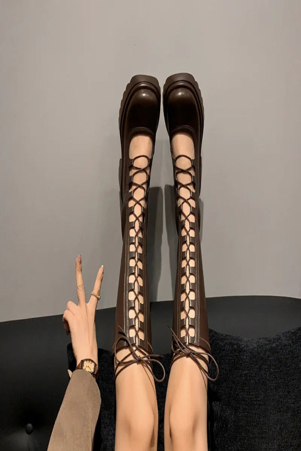 Brown lace-up high-heeled boots on a plain background