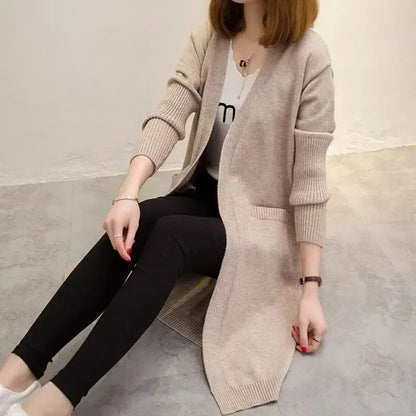Person wearing a beige cardigan sitting on a concrete floor.
