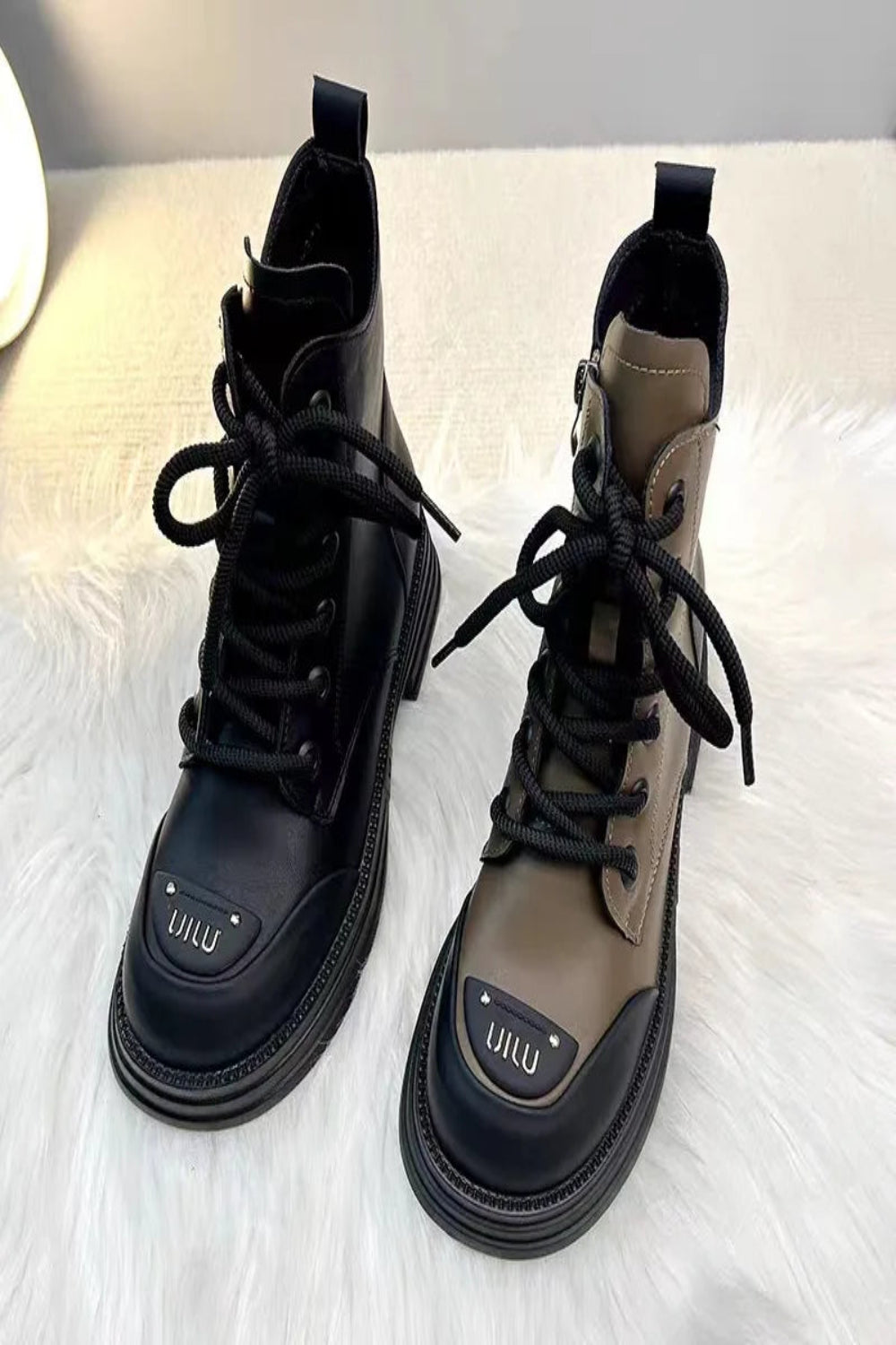 Pair of black and brown boots with 'UILU' branding on a white surface.