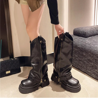 Person wearing black knee-high boots with zippers indoors.