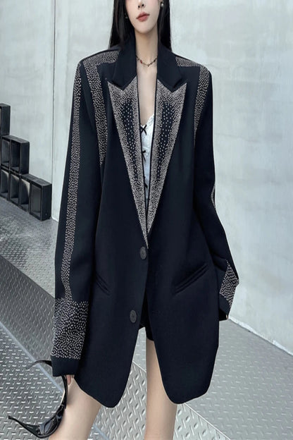 Person wearing a black blazer with decorative trim against a neutral background