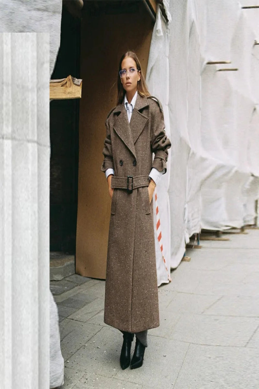 Woman wearing a long brown coat in an urban setting