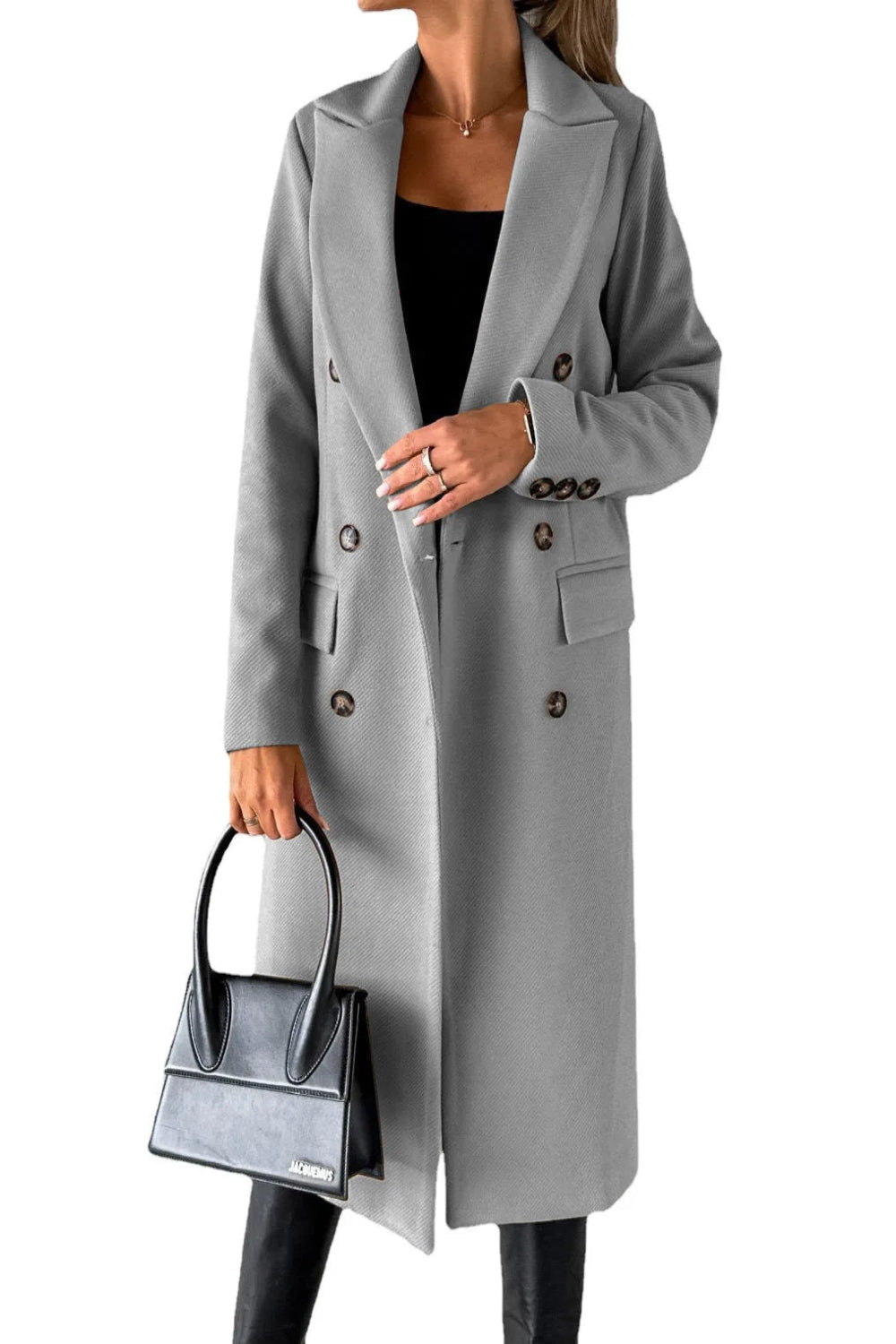 Person wearing a gray coat holding a black handbag on a white background