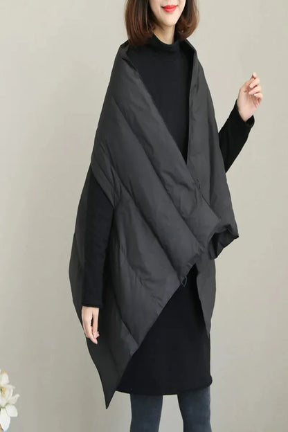 Person wearing a black poncho over a black top on a plain background