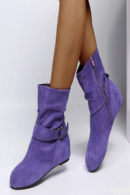 Purple suede boots worn by a person on a white background