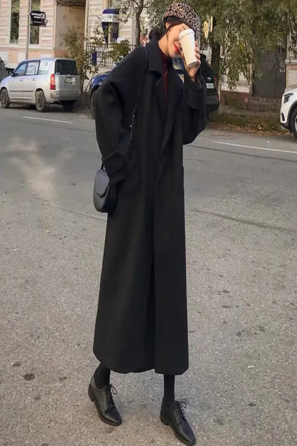 Person wearing a long black coat on a street