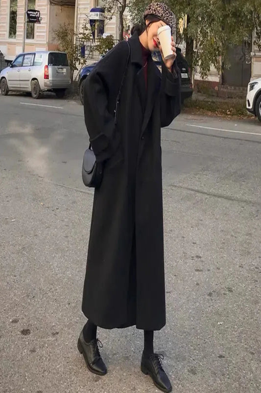 Person wearing a long black coat on a street