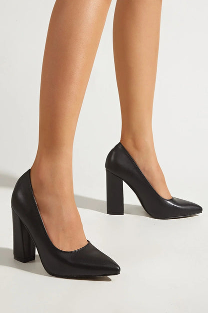 Black high-heeled shoes worn with beige tights on a light background