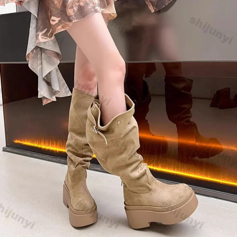 Beige knee-high platform boots worn by a person, with a blurred background.