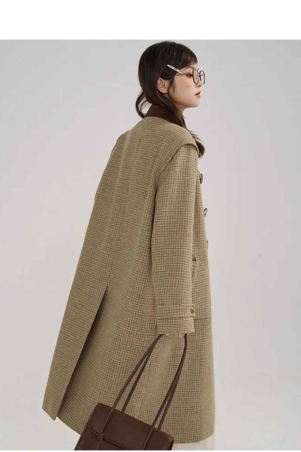 Woman wearing a long green coat with a white background