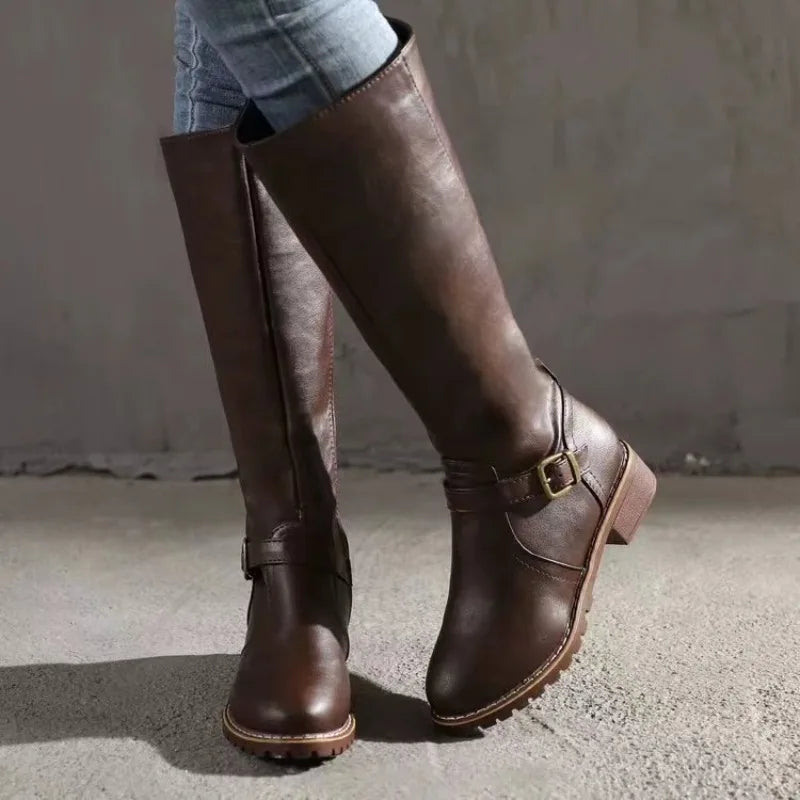 Brown knee-high boots with a buckle on a neutral background
