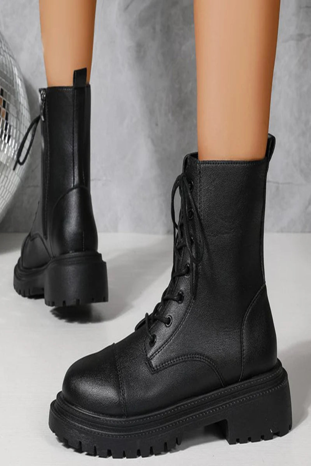 Black leather boots with thick soles on a neutral background