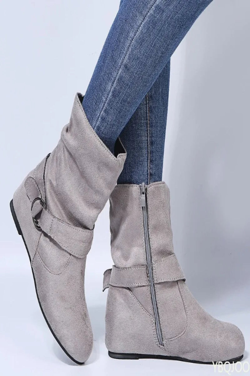 Gray ankle boots with buckles worn with blue jeans on a light gray background