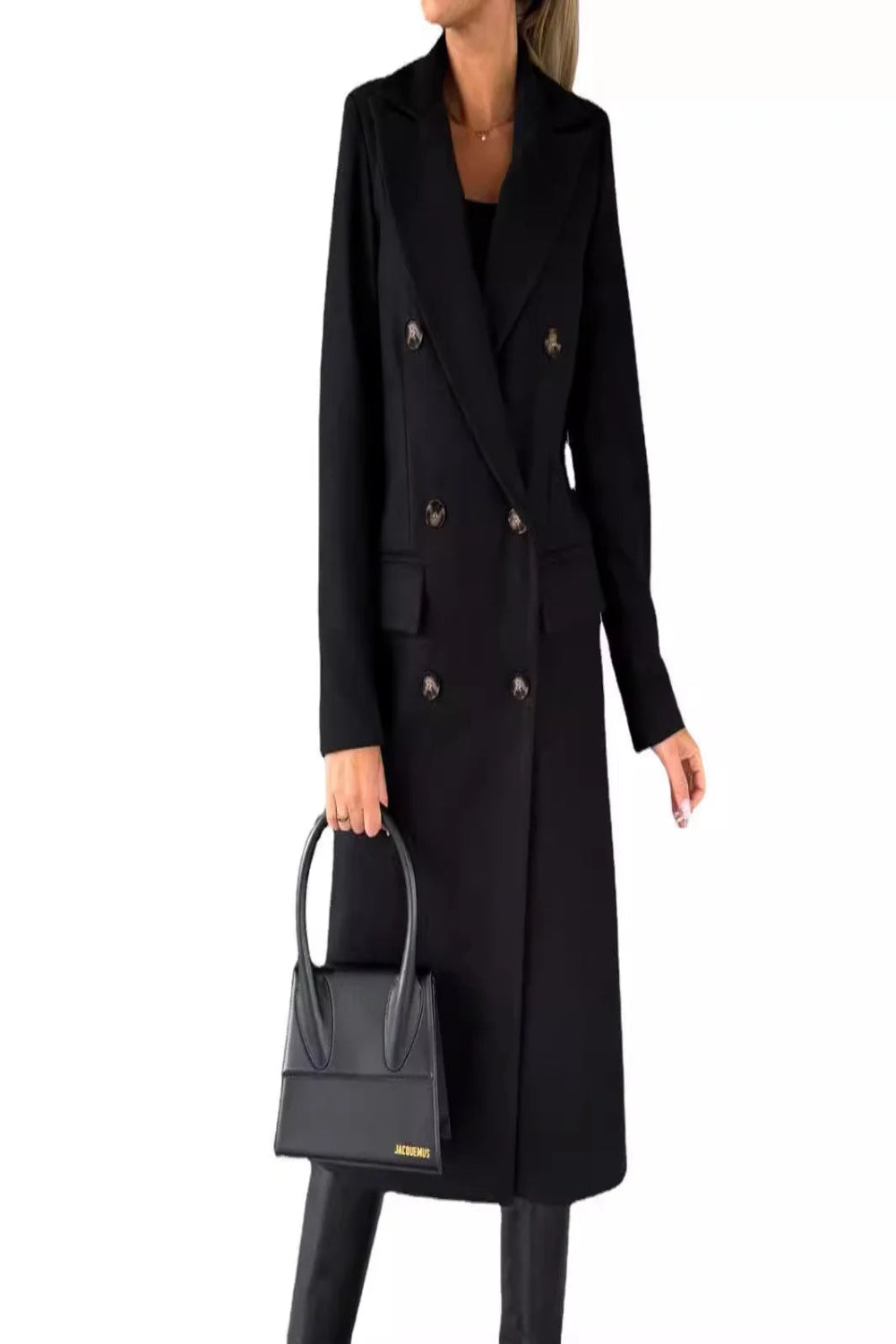Person wearing a black coat holding a matching black handbag on a white background