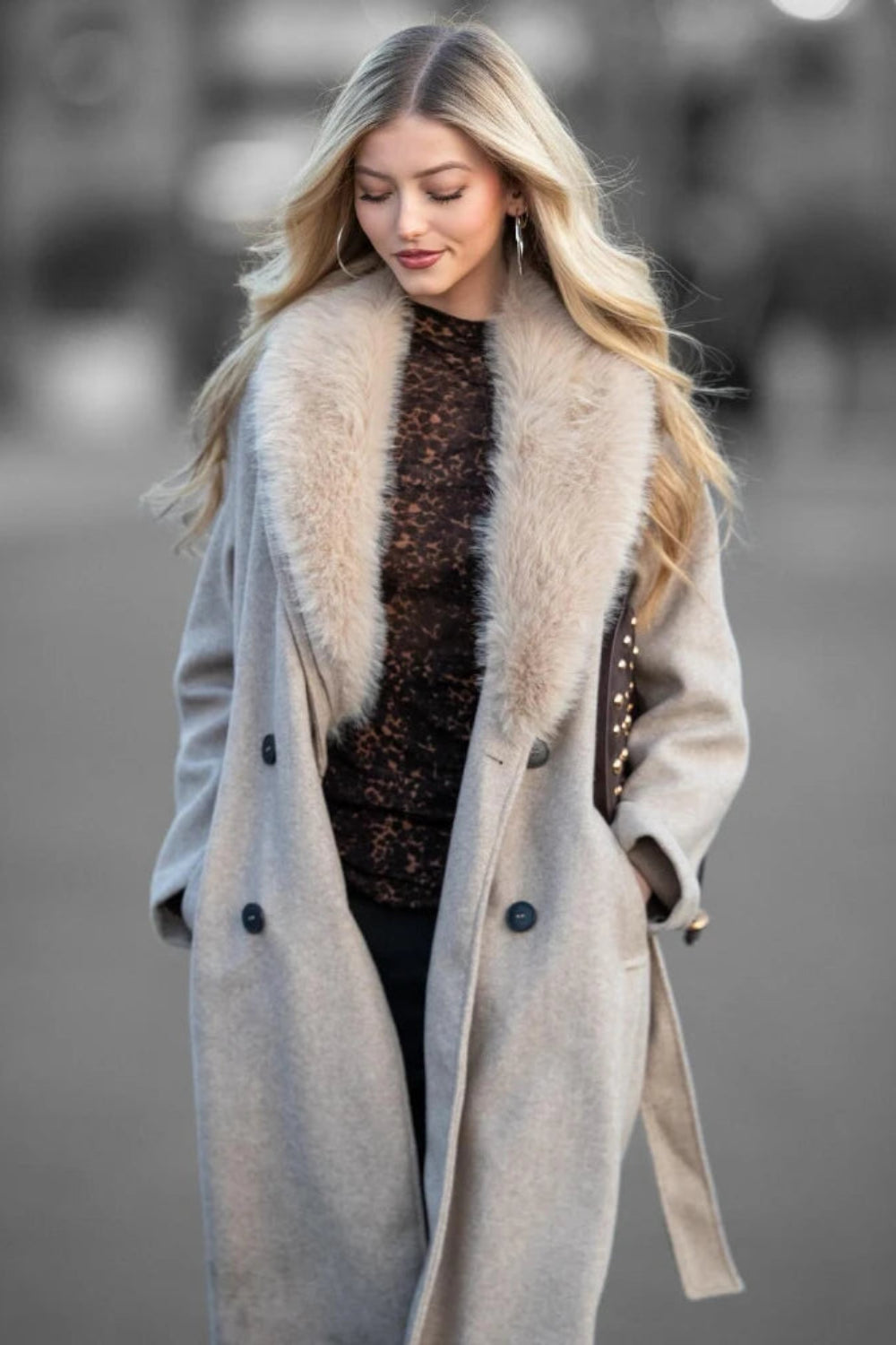 Woman wearing a long coat with a fur collar against a blurred background