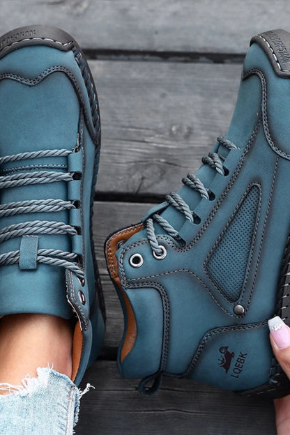 Blue leather boots with brown soles on a wooden floor