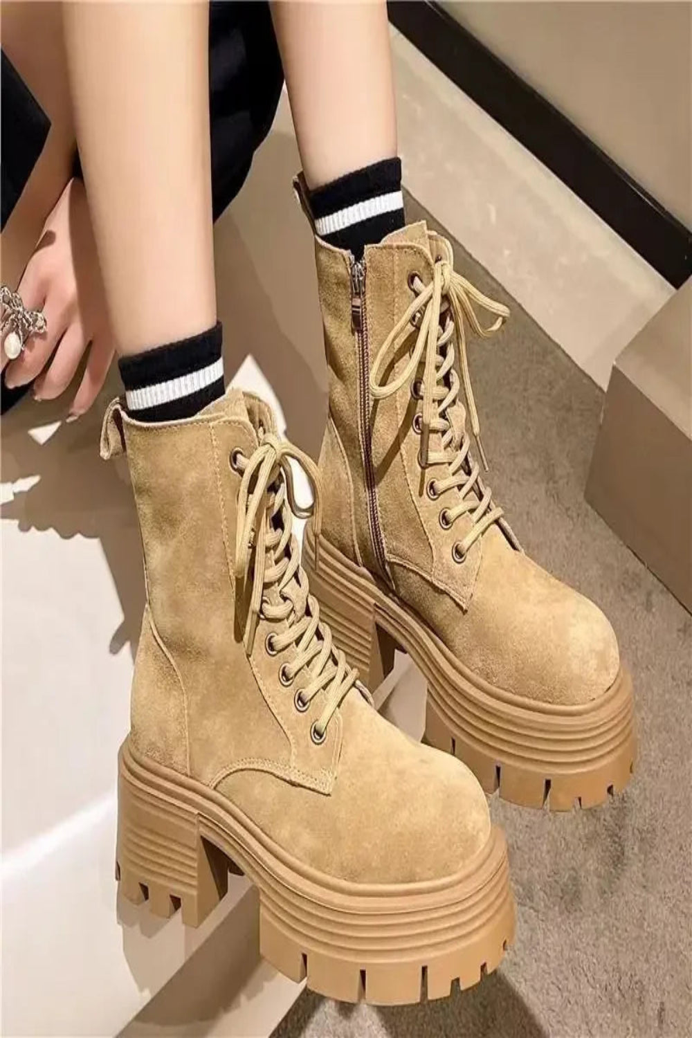 Tan combat boots worn with black and white striped socks on a neutral background