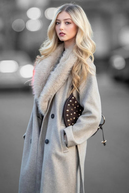 Woman wearing a long coat with a fur collar on a blurred street background