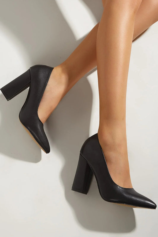 Black high-heeled shoes worn by a person on a light background
