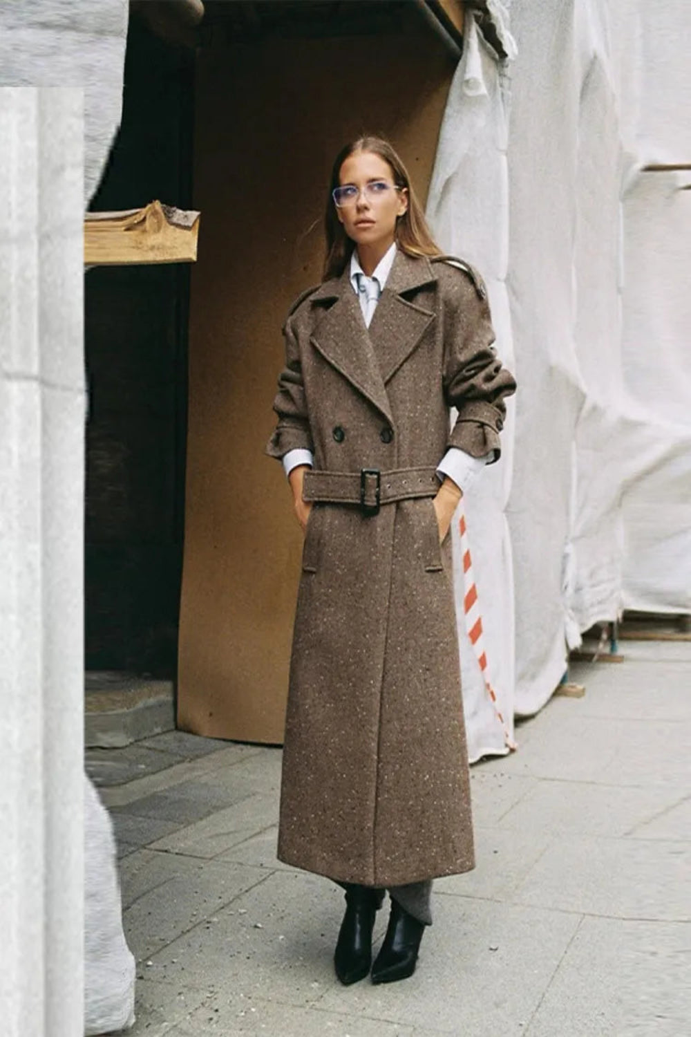 Woman wearing a long brown coat in an urban setting
