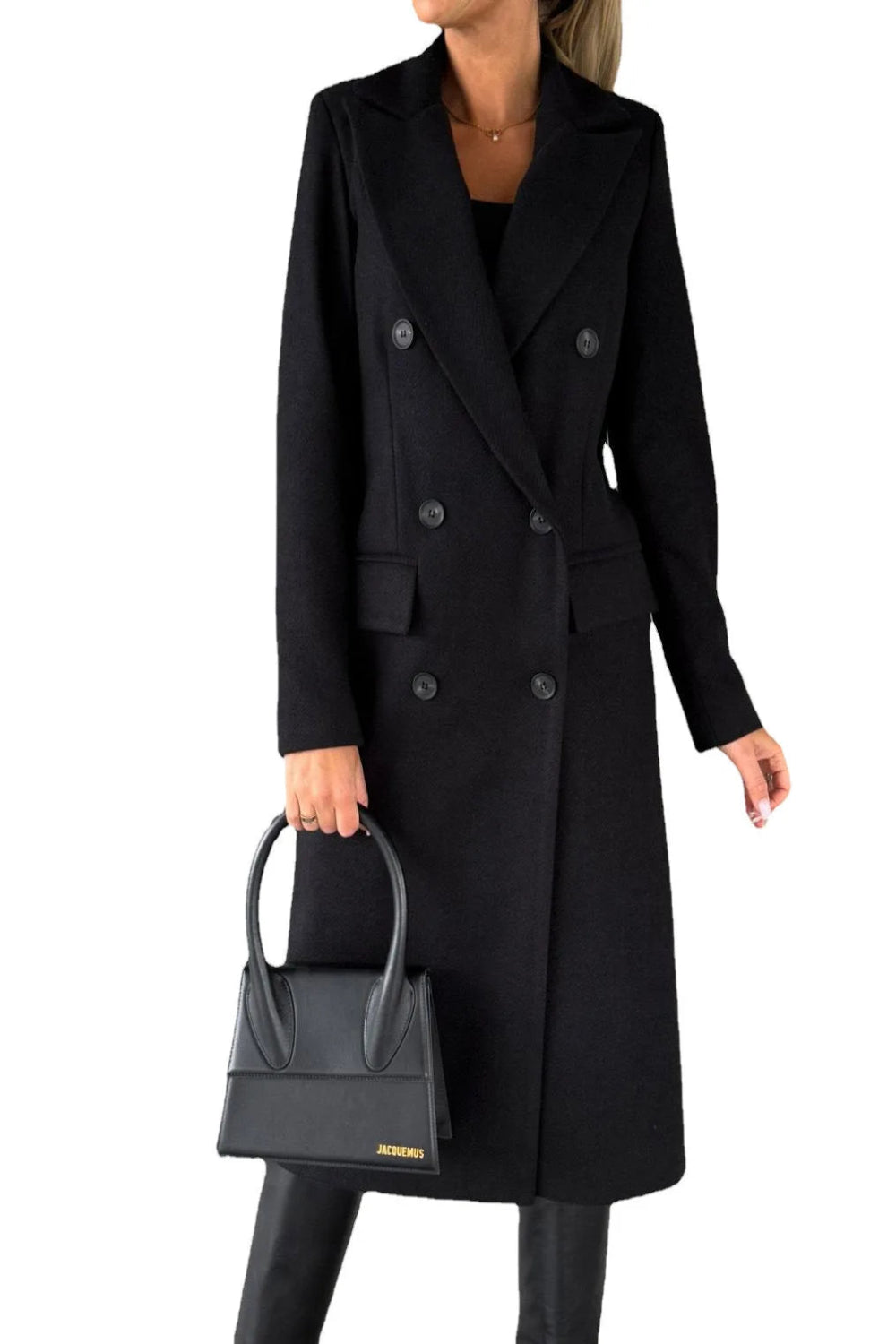 Person wearing a black coat holding a black handbag on a white background