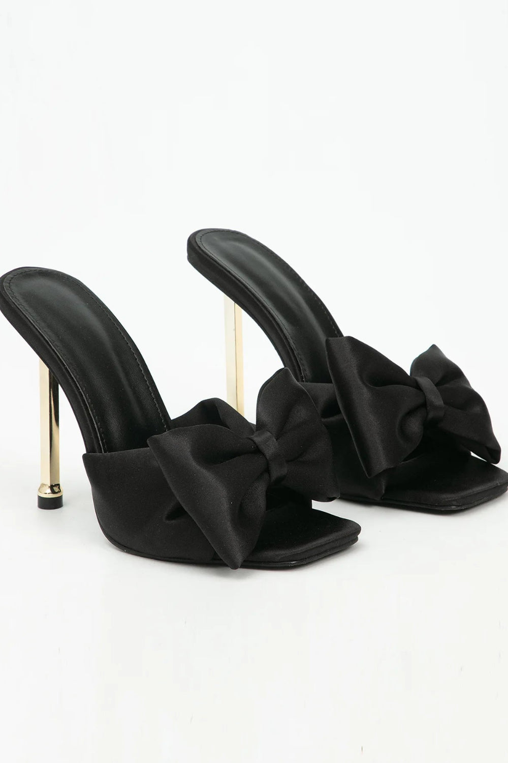 Black high-heeled sandals with bow details on a white background