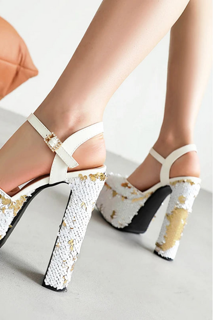 White high-heeled shoes with gold sequins on a light background