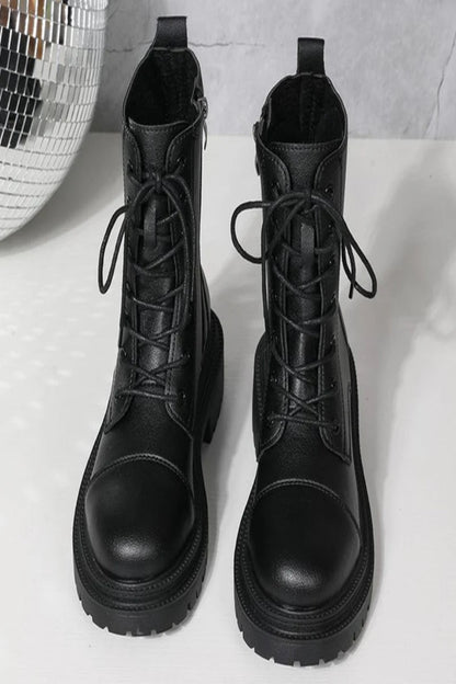 Pair of black lace-up boots on a light gray background