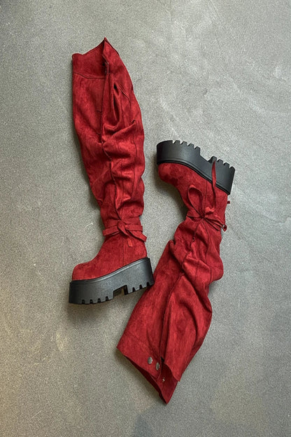 Red suede platform boots with black soles on a gray surface