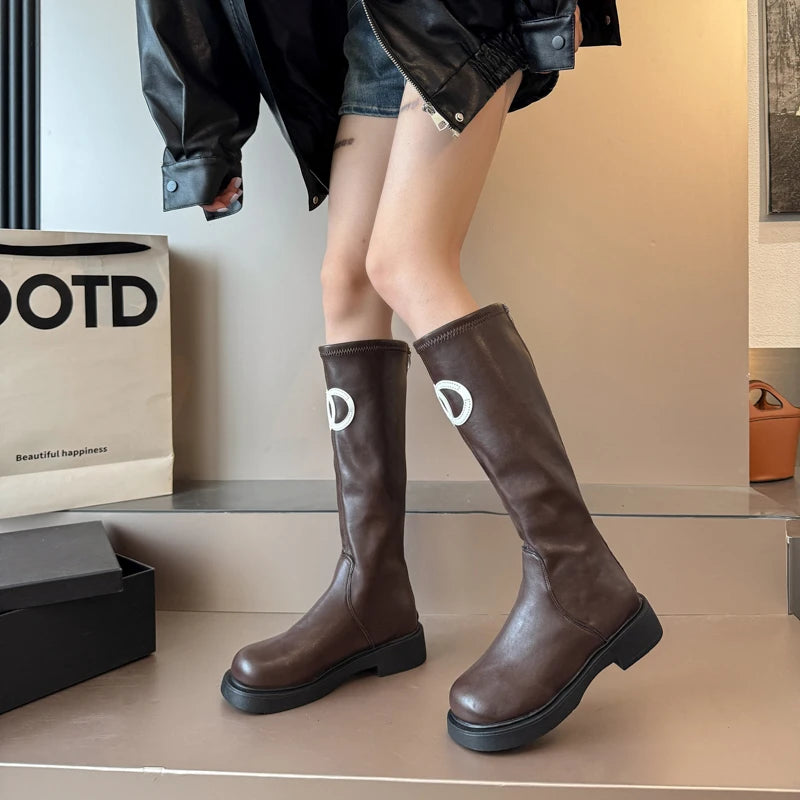 Brown knee-high boots worn by a person with a neutral background