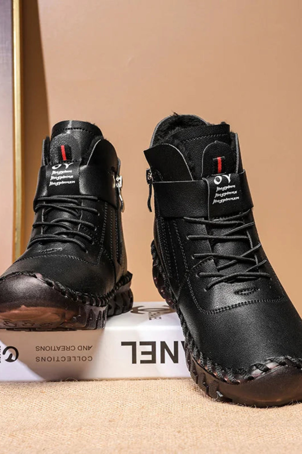 Black high-top boots with a visible brand logo on a beige background