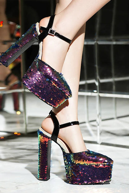 Multicolored sequin high-heeled shoes on a reflective floor.