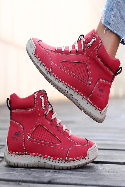 Red high-top sneakers with white soles on a wooden surface