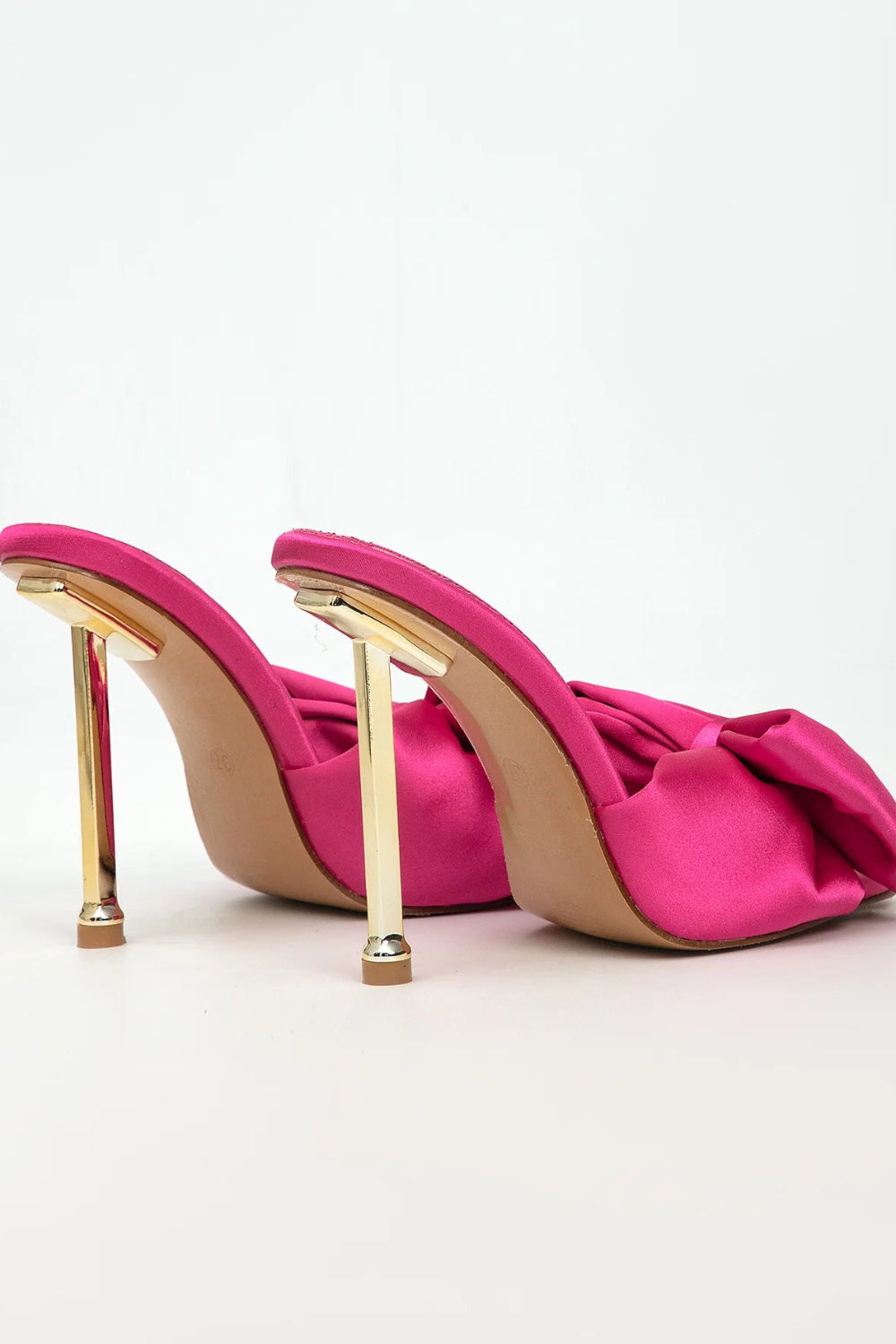 Pink high-heeled shoes with gold heels on a light gray background