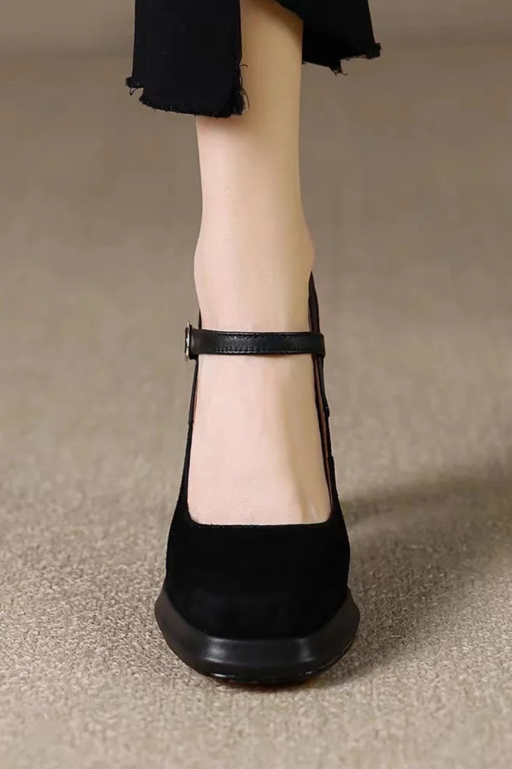 Black shoe worn on a neutral background