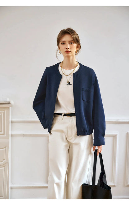 Woman wearing a navy blazer, white shirt, and beige pants in an indoor setting.