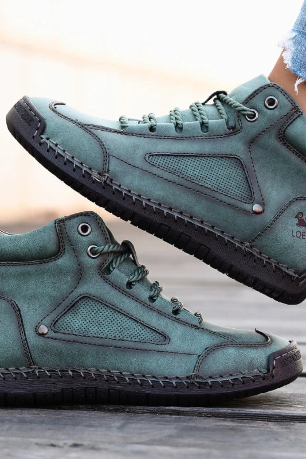 Pair of teal high-top sneakers on a wooden floor with a blurred background