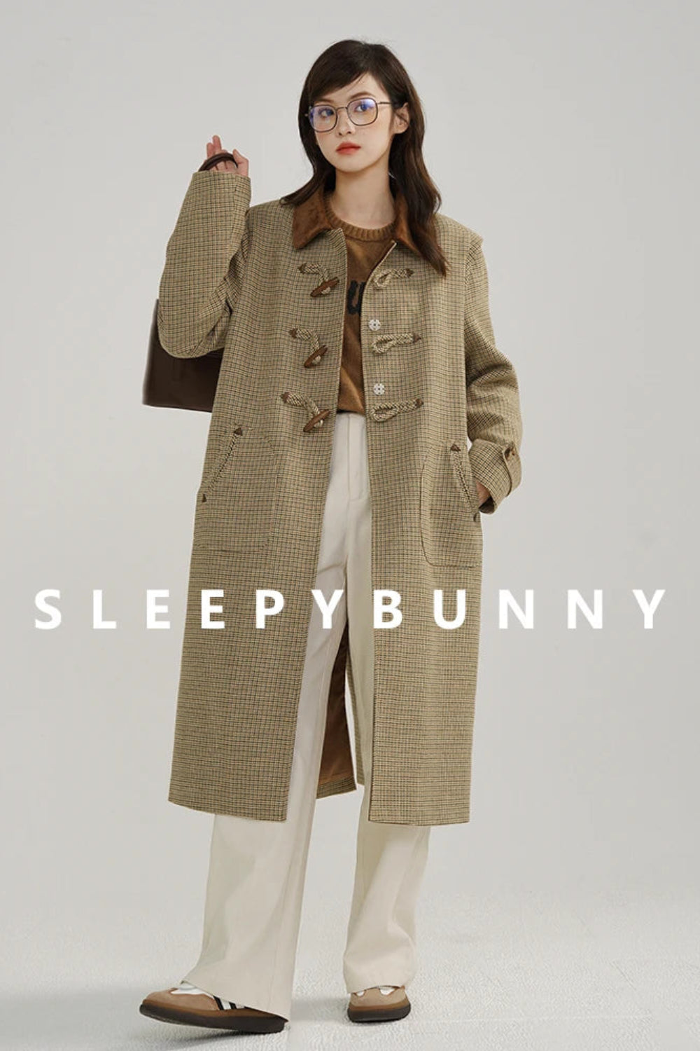 Person wearing a long beige coat with 'Sleepy Bunny' branding