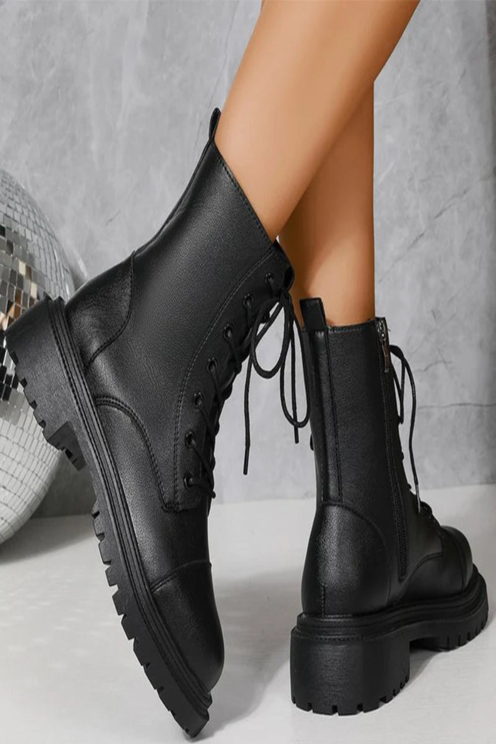 Black leather boots with chunky soles on a neutral background