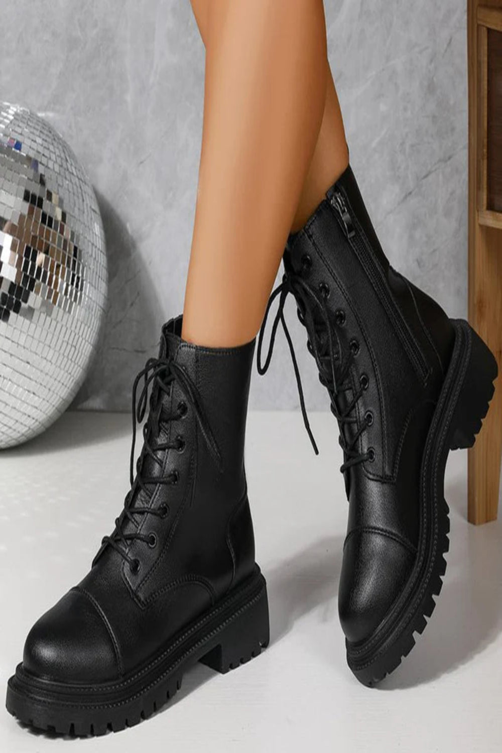 Black leather boots worn with a disco ball in the background