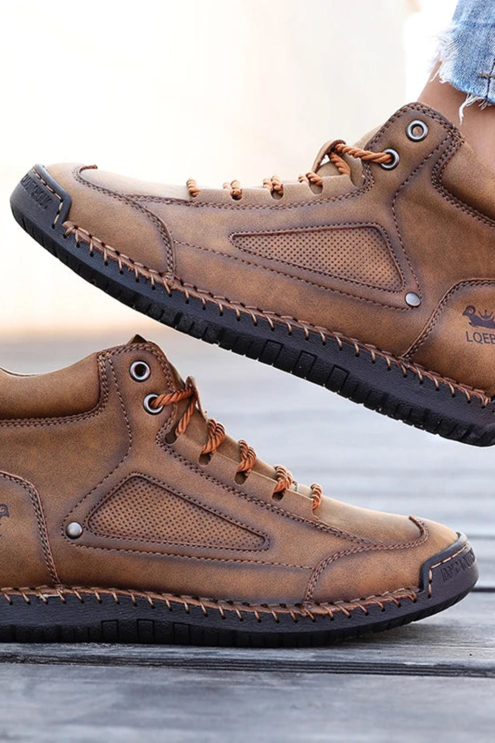 Brown leather boots with black soles on a wooden surface