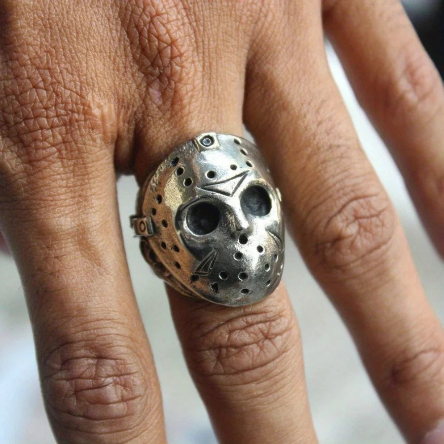 Silver mask ring on a finger with a blurred background